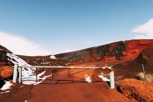 Marsianska landskap på Island. Den röda kratern av Seydisholar vulkanen. Den röda jordbrytningens stenbrott. Vit snö ligger på röd mark, Stängd grind vid ingången. — Stockfoto