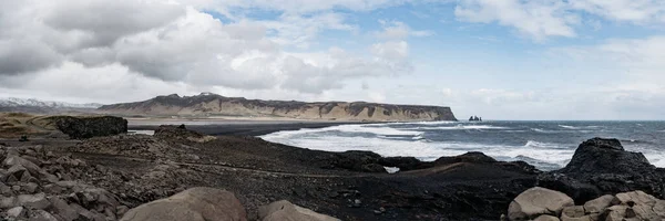 Roca basáltica en la playa de arena negra conocida como playa de Reynisfjara en la costa sur de Islandia en el día que cae la nieve . — Foto de Stock