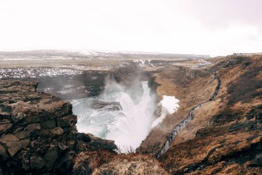 Güney İzlanda 'daki Büyük Şelale Gulfoss, altın yüzükle. Turistler patikada yürür.