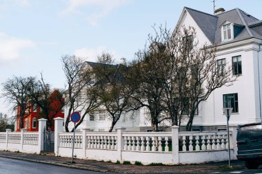 Sokağın köşesindeki ev, İzlanda 'nın başkenti Reykjavik' te sütunları olan güzel beyaz çitli..