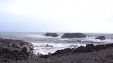Kara kumsalda fırtınalı, kasvetli bir gün. İzlanda, Avrupa 'nın güneyinde Vik Reynisfjara, Atlantik Okyanusu' nda büyük dalgalar.