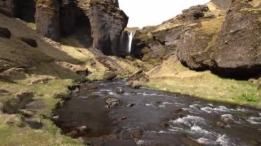 İzlanda 'nın güneyindeki Kvernufoss şelalesine giden yol, Altın Halka üzerinde. Dağ nehri yosun ve sarı otlarla dolu bir vadide.