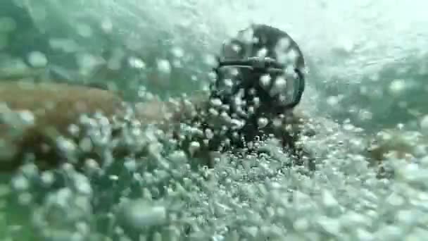 Ansiktet på en dykare som dyker i en mask med en snorkel under vattnet. Långsam undervattensselfie bland luftbubblor. — Stockvideo