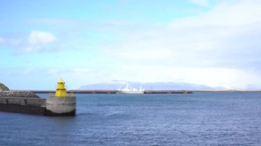 Reykjavik İzlanda 'daki rıhtımdaki deniz feneri. Deniz feneri sarı parlak kule deniz kıyısında. Deniz limanı navigasyon konsepti. Deniz ulaşımı ve seyrüsefer. Deniz manzarası ve parlak deniz feneriyle gökyüzü.