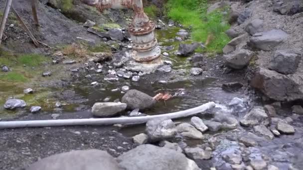 Старый водопровод прорвался через трубу. Вода бьется из-под камней . — стоковое видео