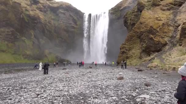 Wasserfall Skogafoss im Süden Islands, auf dem Goldenen Ring. Besucher kamen, um den Wasserfall zu sehen, Touristen spazieren am Fuße des Berges. — Stockvideo