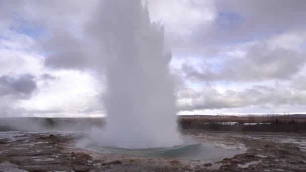 Geysertal in het zuidwesten van IJsland. De beroemde toeristische attractie Geysir. Geothermische zone Haukadalur. Toeristen kijken naar de uitbarsting van Strokkur geiser op de hellingen van Laugarfjall heuvel. — Stockvideo