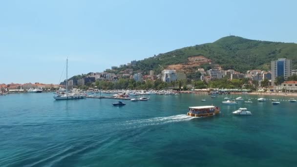 O barcă cu turiști înoată până la malul orașului Budva, lângă docul cu barca, în Muntenegru . — Videoclip de stoc