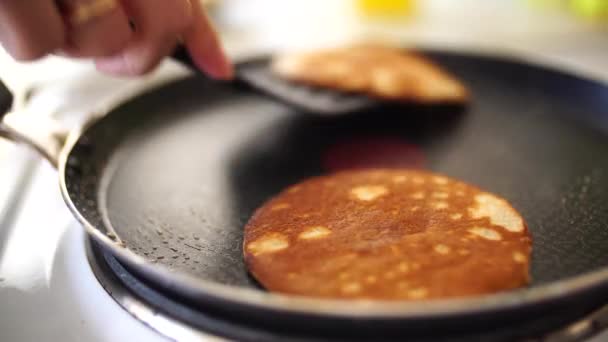 De meisjes handen in een blauw schort worden verwijderd uit de pan van de pannenkoek met een spatel. Zet de pannenkoeken in een stapel. — Stockvideo