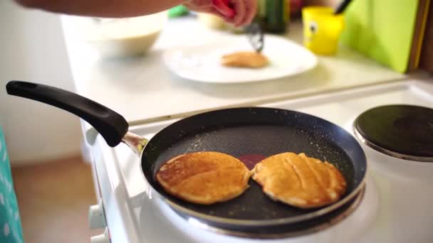 Mam maakt pannenkoeken. Vrouwen handen verwijder de punks met een spatel uit de pan. — Stockvideo