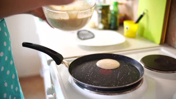 Vrouw chef gieten pannenkoeken beslag op een koekenpan. — Stockvideo