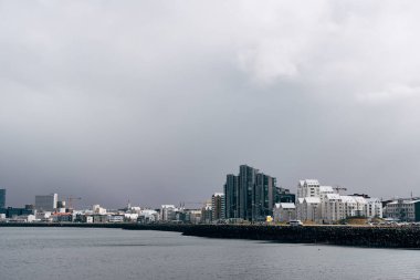 İzlanda 'nın başkenti Reykjavik' in rıhtımındaki çok katlı modern yüksek binalar. Atlantik Okyanusu 'nun kıyısında sakin bir su vardır. Bulutlu gökyüzü, bir kar fırtınası yaklaşıyor.