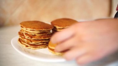 Kız tavadan krepleri alıyor ve tabağa koyuyor..