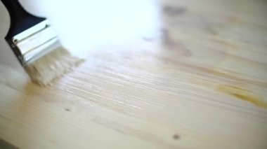 Erkekler ahşap hamuru beyaz boya fırçasıyla boyarlar..