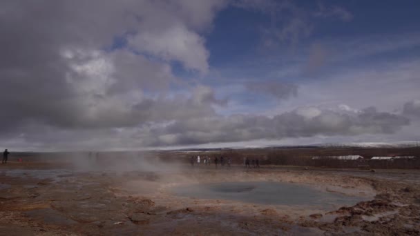 Долина Гейзер на південному заході Ісландії. Знаменита туристична атракція Гейзер. Геотермальна зона Haukadalur. Туристи спостерігають виверження гори Строккур на схилах пагорба Лаугарфйолл.. — стокове відео
