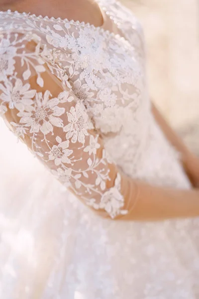 Close-up of a sleeve with lace wedding dress on the bride. Fine-art wedding photo in Montenegro, Perast.