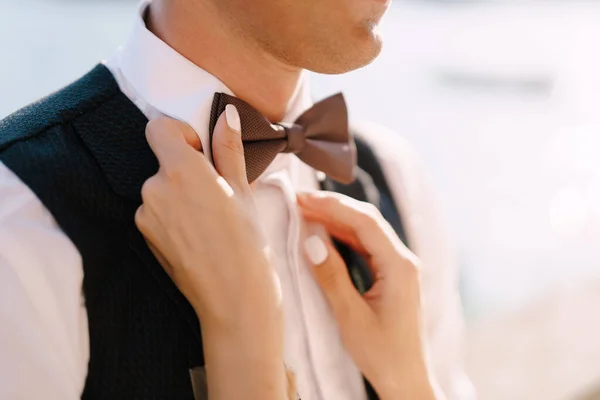 Fine-art wedding photo in Montenegro, Perast. A closeup of the hands of a bride. He plays with his fingers with a grooms bow tie. — Stock Photo, Image