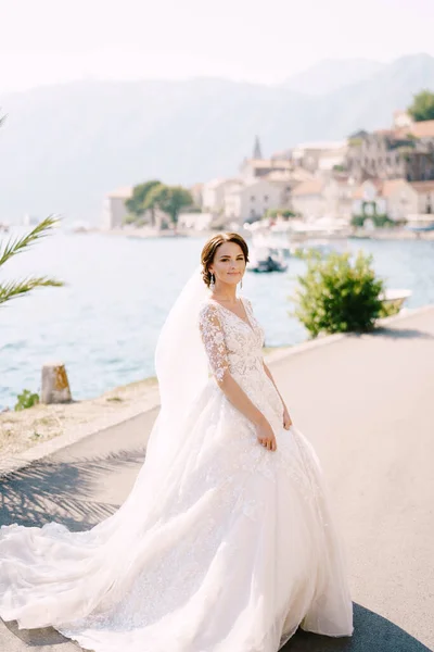 Potret seorang pengantin dalam gaun krim di bawah pohon palem di latar belakang laut. Foto pernikahan seni rupa di Montenegro, Perast. — Stok Foto