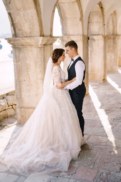 Fine-art wedding photo in Montenegro, Perast. Wedding couple cuddles in old stone columns. — Stock Photo, Image