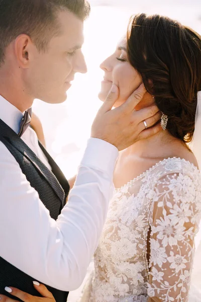 Fine-art wedding photo in Montenegro, Perast. Close-up portrait of a wedding couple, the groom strokes the bride on the cheek with his hand at sunset. — Stock Photo, Image