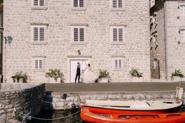 Karadağ 'da sanat eseri bir düğün fotoğrafı, Perast. Gelin ve damat eski beyaz bir evin arka planında ve demirli kanolarla dans ediyorlar..