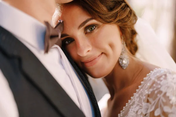 Close-up portrait of a bride looking at the camera, laid her head on the grooms chest. Beautiful wedding couple. Fine-art wedding photo in Montenegro, Perast. — Stock Photo, Image