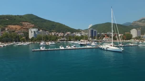 Karadağ 'ın eski Budva kenti yakınlarındaki yat ve tekneler için bir marina. Küçük bir turist teknesi gök mavisi sularda yelken açar.. — Stok video