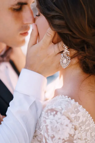 Gros plan, le couple s'embrasse presque. Le marié caresse la main de la mariée sur la joue. Beaux-arts photo de mariage en Monténégro, Perast . — Photo