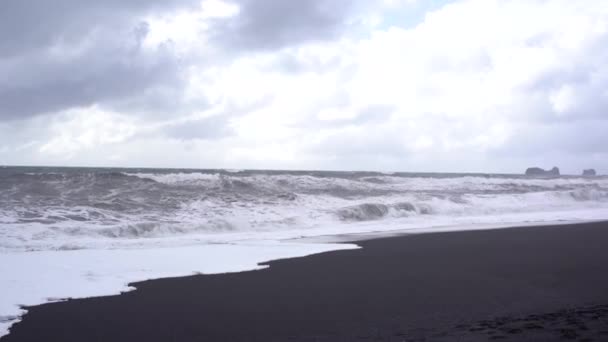 Bewölkter Himmel, Wellen im Atlantik und schwarzer Sand am Strand von Vik, Island. — Stockvideo