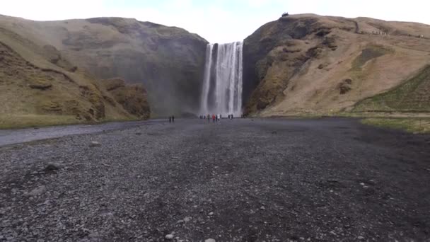 Skogafoss waterfall in the south of Iceland, on the golden ring. Visitors came to see the waterfall, tourists walk at the foot of the mountain. — Stock Footage Skogafoss waterfall in the south of Iceland, on the golden ring. Visitors came to see the waterfall, tourists walk at the foot of the mountain. Royalty Free Stock Video
