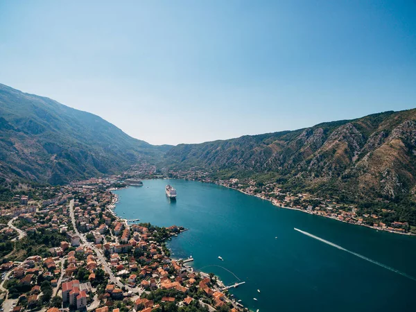 Kotor Bay z lotu ptaka, strzał z powietrza z drona. Liniowiec zacumowany w wodach zatoki, naprzeciwko starego miasta Kotor. Dachy domów w mieście Dobrota. — Zdjęcie stockowe