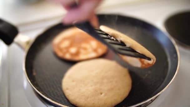 Kvinnors händer med en spatel vända pannkakor i en stekpanna. — Stockvideo