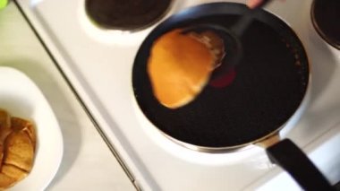 Mavi önlüklü kızlar spatulayla pankekin tavasından çekiliyorlar. Krepleri yığının içine koyar..