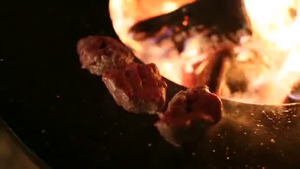 Närbild kött biff förbereds på en rund stål järn utomhus grill med en spishäll och en öppen eld i mitten. — Stockvideo