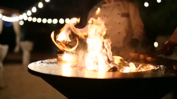 Chefs maken steaks op een rooster. Vleesbiefstuk wordt bereid op een ronde stalen buitengrill met een kookplaat en een open vuur in het midden. — Stockvideo