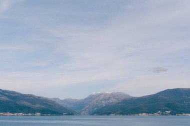 Karadağ 'ın Kotor Körfezi üzerinde kar beyazı bulutlarıyla mavi gökyüzü.