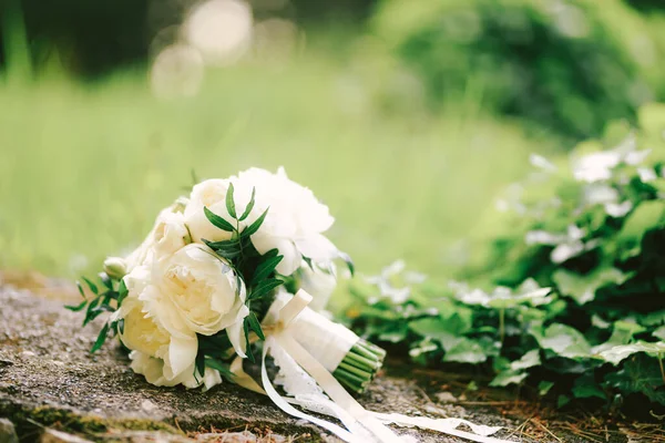 Ramo nupcial de peonías con cintas blancas en la piedra . — Foto de Stock