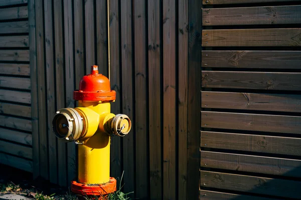 Gele brandkraan met rode dop en zilveren deksels, Op een houten ondergrond. — Stockfoto