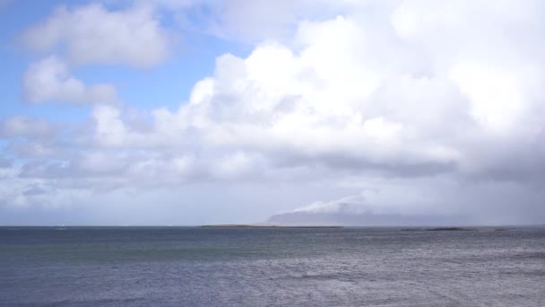 Ein schneebedeckter Berg an der Atlantikküste Islands. Blick von der anderen Seite oder vom Meer aus. Bewölktes Wetter, dichte Wolken. — Stockvideo