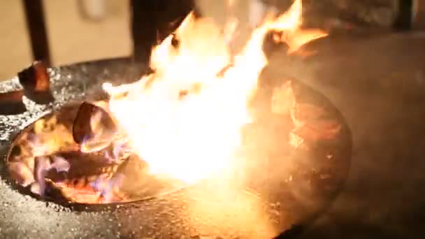 Vleesbiefstuk wordt bereid op een ronde stalen buitengrill met een kookplaat en een open vuur in het midden. — Stockvideo