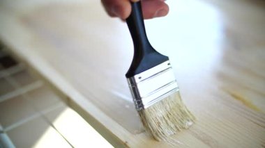 Erkekler ahşap hamuru beyaz boya fırçasıyla boyarlar..