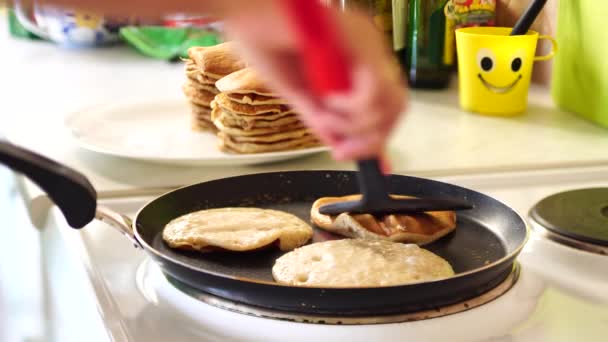 Une cuisinière retourne une spatule de crêpes dans une poêle . — Video