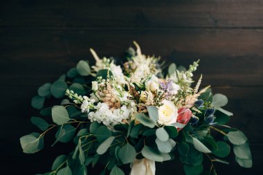 gelin buketi beyaz ve kremalı güller, okaliptüs ağacı dalları, protea, eryngium, delphinium ve beyaz kurdele