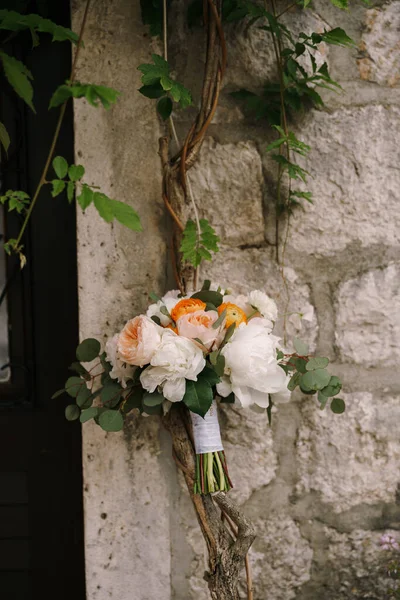 Karangan bunga pengantin putih, mawar krim, buttercups oranye dan cabang pohon eukaliptus di dekat dinding di cabang wisteria — Stok Foto
