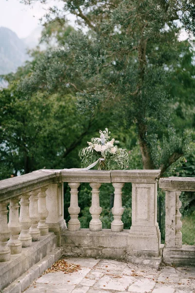 Buquê nupcial de peônias brancas e creme, rosas, veronica, delphinium, ramos de eucalipto com fita branca no corrimão de uma escadaria antiga — Fotografia de Stock