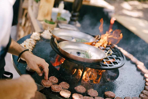 Szef kuchni grilluje klopsiki do mini hamburgerów na grillu. — Zdjęcie stockowe