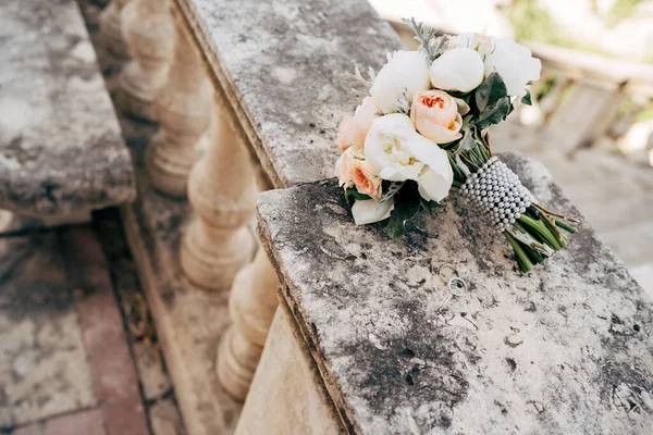 Buket pengantin putih dan krim peonies, mawar, salal, artemisia dengan pita mutiara di pagar tangga kuno — Stok Foto