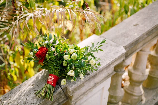 Buket pengantin mawar merah dan merah muda, cabang boxwood, tidak mekar tunas bunga putih dan pita merah dengan bros di pagar tangga kuno — Stok Foto