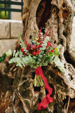 Burgundy şakayık demeti, kırmızı güller, okaliptüs ağacı dalları, eryngium, bebek nefesi, celosia ve zeytin ağacında kırmızı kurdele.
