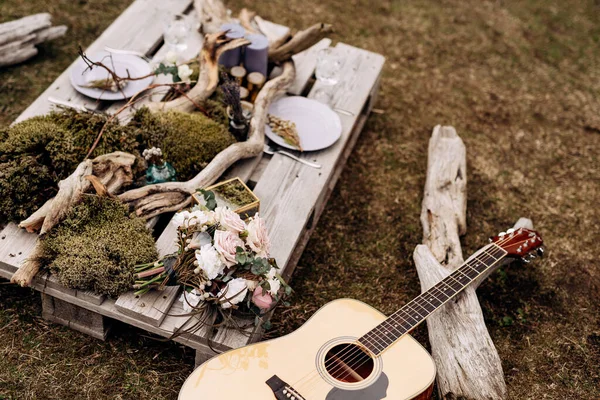 Buket pengantin mawar putih, brunia dan leucadendron, buket lavender kering pada tamasya romantis dengan gitar, dekorasi meja, lilin, cabang kering dan lumut di Islandia — Stok Foto